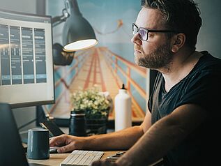 Man working from home contemplating looking at screen monitor.